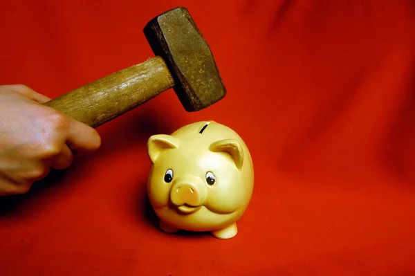 smashing a piggy bank with a hammer, on red background