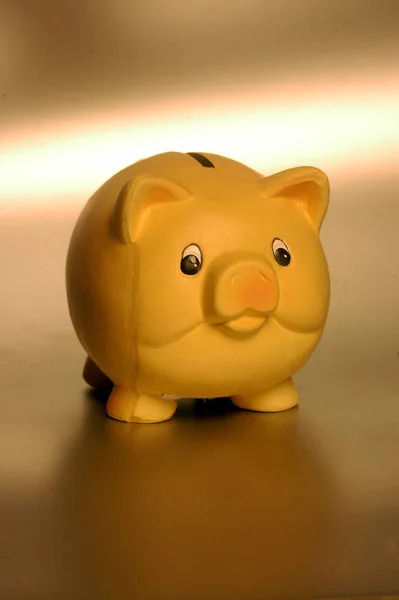yellow piggy bank on a desk, warm light in the background
