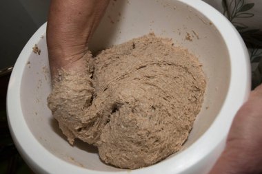 Kadın ev yapımı ekmek hamuru yapıyor, ekmek hamurunu elle yoğuruyor.