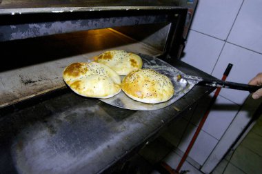 Üç tane düz ekmek ya da taze pişmiş susamlı pide alıyorum.