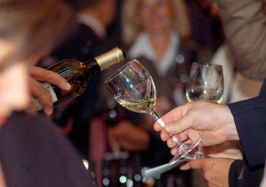 Bir bardağa beyaz şarap doldurmak, insanları arkada bulanıklaştırmak.