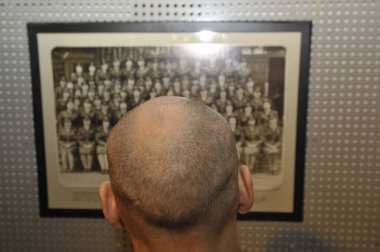 Kel kafalı bir adam siyah beyaz resme bakıyor.