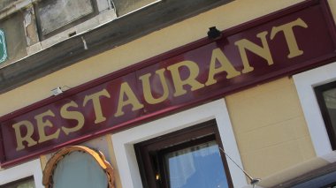 Binada restoran tabelası, kırmızı tabelada sarı harfler.