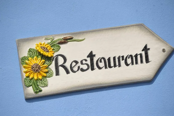 建物のレストランサイン 太陽の花の白い看板の黒い文字 青い家の壁 — ストック写真