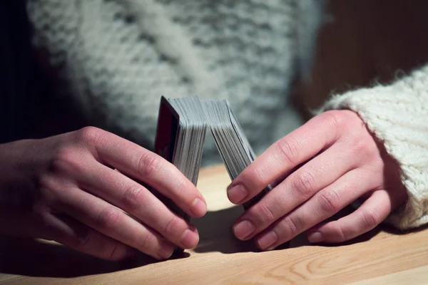 two hands holding cards before shuffling the cards of card game