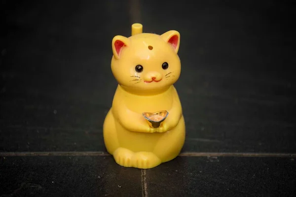 yellow toy cat standing in the center of black tiled floor