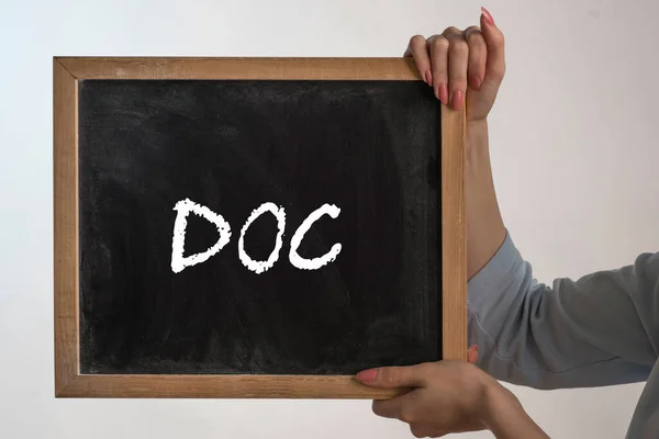 woman holding up a blackboard that says DOC, white background