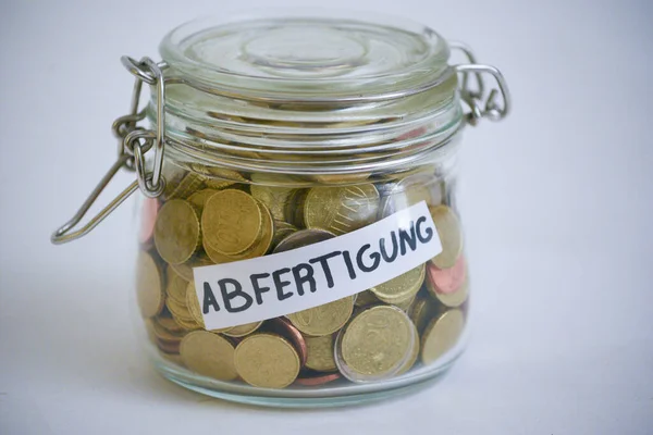 Jar full of coins with a label saying Abfertigung (financial compensation)