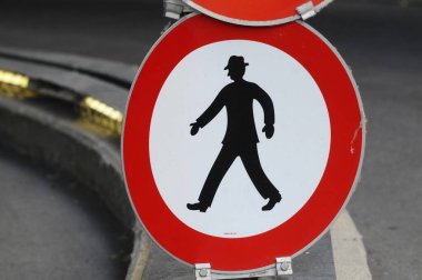 Caddedeki yaya trafik levhası, üzerinde bir yayanın resmi olan kırmızı daire.