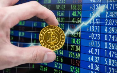 Borsa çizelgesinin önünde altın bir bitcoin.