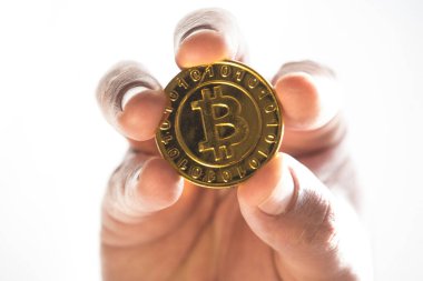 Elinde altın bir bitcoin tutarak, elektronik para birimini temsil ediyor.