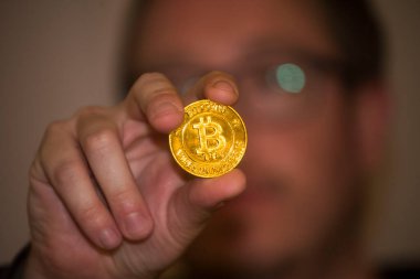Elinde altın bir bitcoin tutarak, elektronik para birimini temsil ediyor.