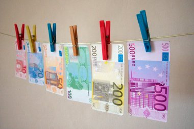 Bir çamaşır ipinde asılı sahte para, euro banknotları ve çamaşır mandalları