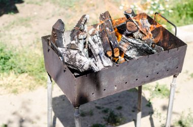 Yakacak odun ızgarada yanıyor. Kömürler barbekü hazırlığı için hazırlanıyor.