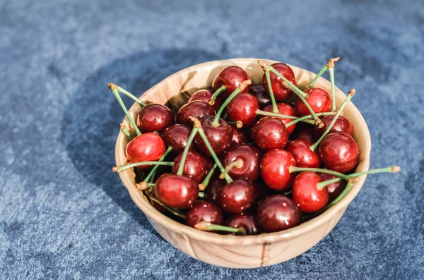 Kahverengi bir kasede kiraz. Gri arka planda taze kiraz yakın plan. Yaz meyveleri. Bahçe konsepti