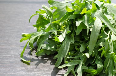 Arugula kahverengi ahşap arka planda, doğrudan güneş ışığı altında. Sağlıklı yeme kavramı