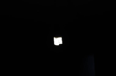 Karanlıkta soğuk bir ampul. Karanlık bir odada ışık sarmalı lamba.