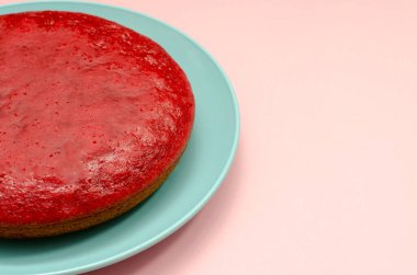 Pembe arka planda turta kırmızıdır. Mavi tabakta meyveli turta