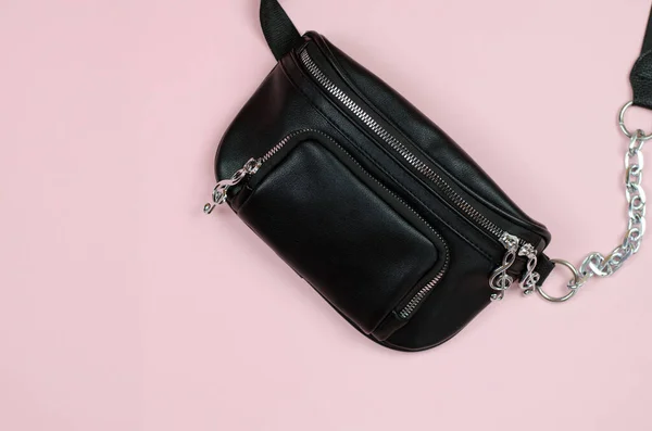 Banana bag. Black leather belt bag on a pink background. Stylish women's handbag.