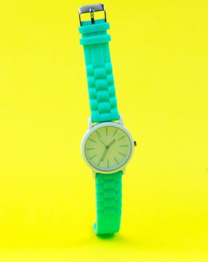 Zarif kadınların saati sarı arka planda asılı duruyor. Kadın aksesuarları.