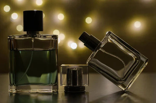 Three bottles of men\'s perfume on the background of festive lights