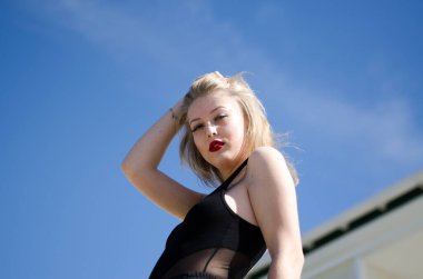 Gökyüzü arka planında genç ve güzel bir kız. Yatay fotoğraf. Sarışın.