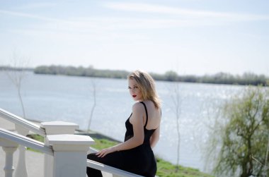 Nehrin arka planında genç sarışın bir model. Yatay fotoğraf. Doğadaki kız