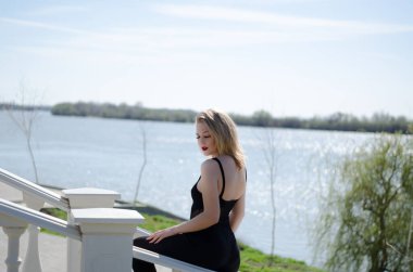 Nehrin arka planında genç sarışın bir model. Yatay fotoğraf. Doğadaki kız