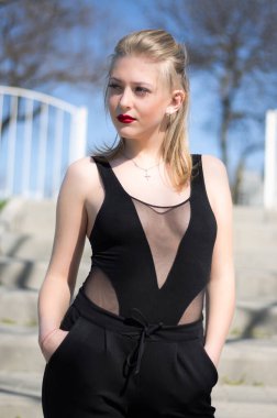 Güzel, genç bir model. Doğada sarışın. Dudaklarında kırmızı ruj var. Siyah cisim içinde model