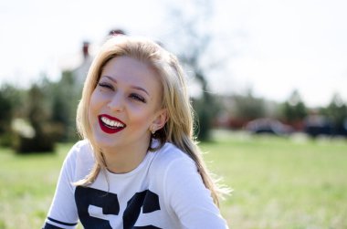 Genç sarışın bir mankenin portresi. Parktaki fotoğraf. Genç bir kız gülümsüyor.