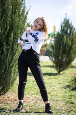 Genç sarışın model. Dikey fotoğraf. Parktaki fotoğraf. Genç bir kız gülümsüyor.