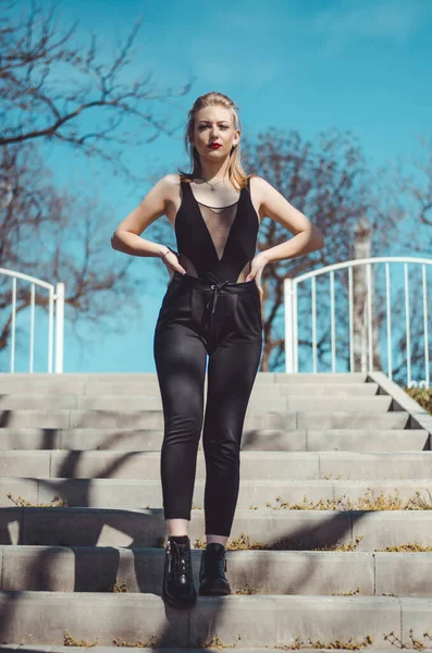 Güzel, genç bir model. Doğada sarışın. Dudaklarında kırmızı ruj var. Siyah cisim içinde model