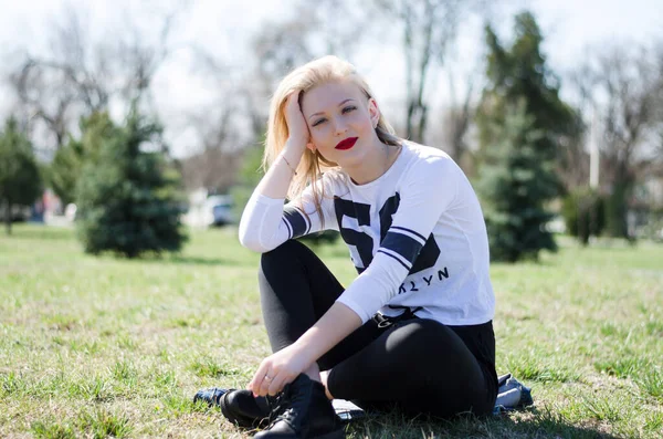 Güzel kız gülümsüyor. Dudaklarında kırmızı ruj var. Doğadaki kız. Sarışın.