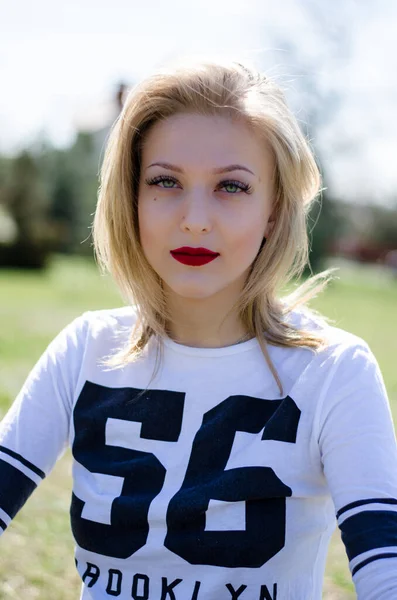 Genç sarışın bir mankenin portresi. Parktaki fotoğraf. Genç bir kız gülümsüyor.