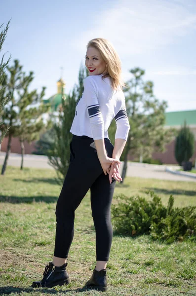 Genç sarışın model. Dikey fotoğraf. Parktaki fotoğraf. Genç bir kız gülümsüyor.