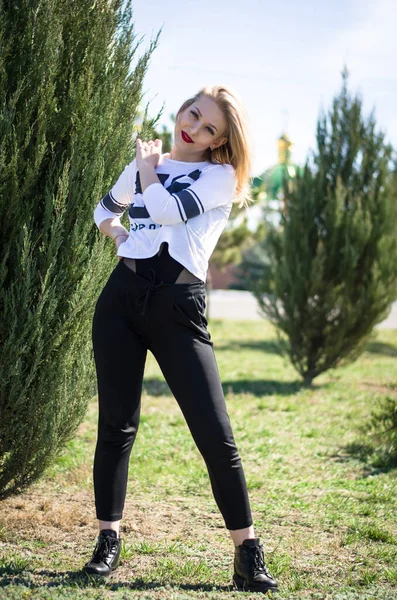 Genç sarışın model. Dikey fotoğraf. Parktaki fotoğraf. Genç bir kız gülümsüyor.