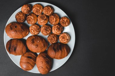 Siyah arkaplanda farklı boyutlarda kapkekler ve metin için boşluk.