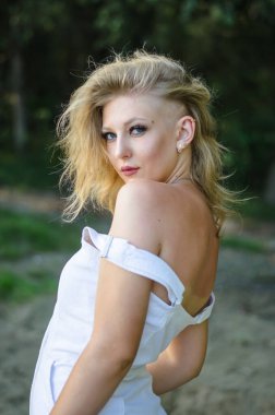 Parkta şık saç stili olan beyaz elbiseli genç bir manken..