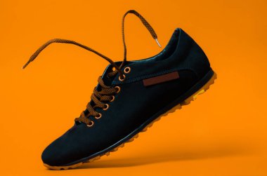 Turuncu arka planda şık siyah ayakkabılar. Uçan ayakkabılar ve bağcıklar.