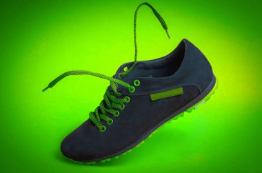 Yeşil arka planda yeni siyah ayakkabılar. Uçan bağcıklı spor ayakkabıları
