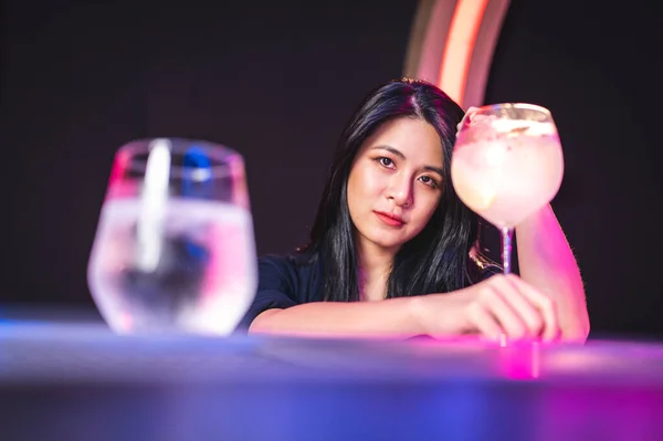 Gece kulübünde bir bardak içki içen Asyalı güzel bir genç kadın.