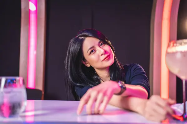 Barda bir bardak kokteyl içen genç bir kadın. 