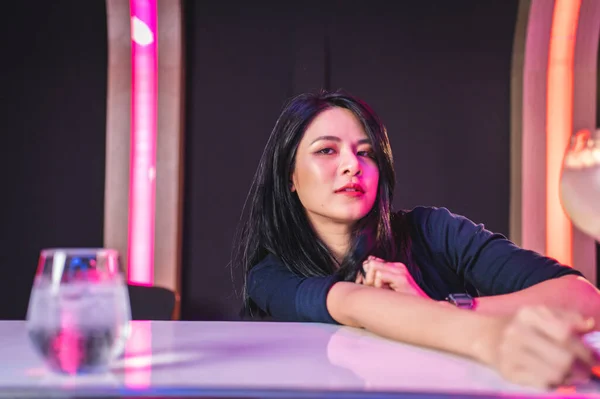Barda bir bardak kokteyl içen genç bir kadın. 