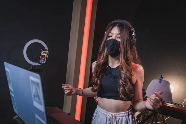 Genç kız tıbbi maske takıyor stüdyoda müzik yapıyor.