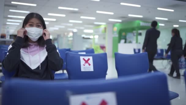 Covid 19大流行病期间的空港 亚洲妇女戴着白色的医疗面罩坐在椅子上 社会疏远标志长椅的概念 屋外禁止检疫保护 旅游保险 — 图库视频影像