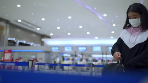 アジアの女性の移動乗客は 出発時刻表のスクリーン 空港ターミナルで 故郷のCovid 19パンデミック 新しい正常な 飛行時間のスケジュールを残す移動の上に保護マスクスタンドを着用します — ストック動画