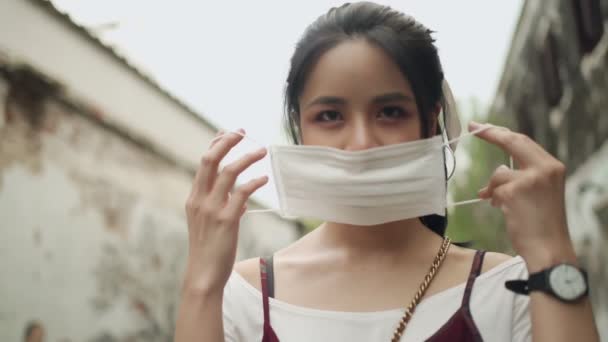 魅力的なフェアスキンアジアの女性は 回転しながら白い保護マスクを着用 コロナ防止 木の背景 日タイム自然光 新しい正常な 屋外のシーン — ストック動画