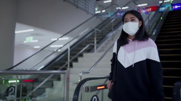 亚洲女人戴着防护面具 从飞机场的自动扶梯上下来 眼镜蛇 19大流行 新的正常社交距离 走下自动扶梯 室内建筑 公共社交楼梯 — 图库视频影像