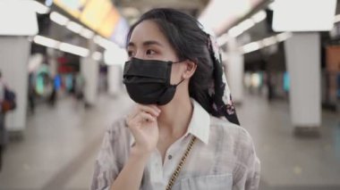 Siyah maskeyi çıkaran Asyalı kadın, metro istasyonunda dikilirken, covid-19, metro istasyonundaki kız, yeni normal yaşam tarzı, kendini koruma, toplu taşıma, sosyal mesafeler