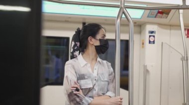 Çekici Asyalı kadın metro duruşu ve metro içinde dengelemek için metro direği tutuyor. Şehir merkezi şehir yaşamı salgını sırasında. Toplu taşımada yeni bir normal.